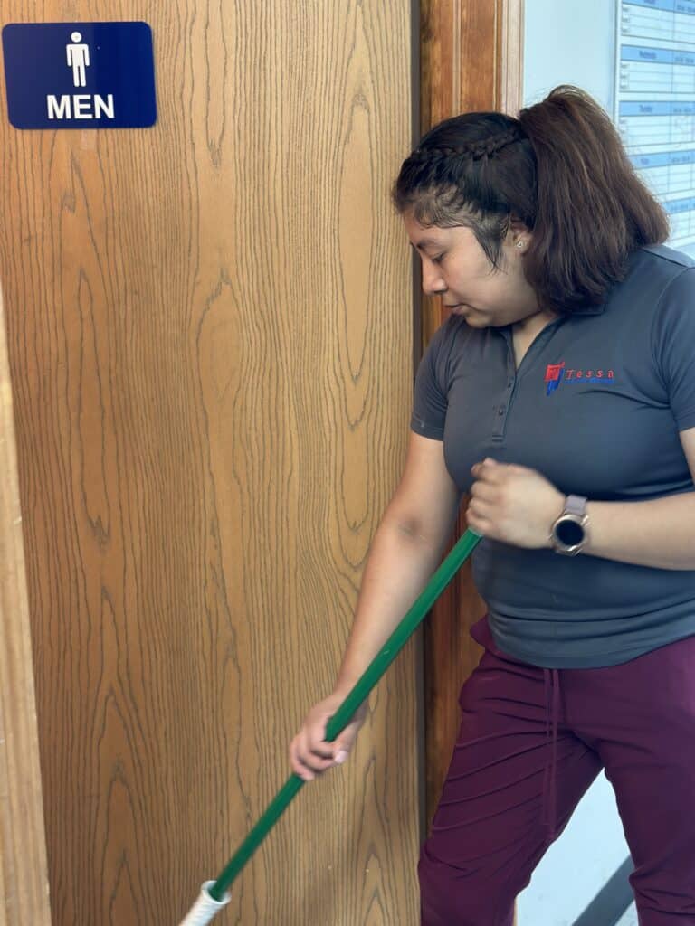 tessa cleaning worker cleaning men's bathroom